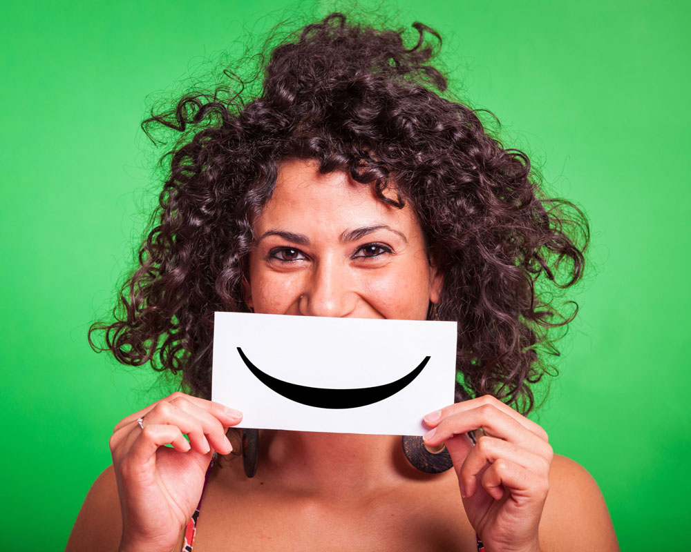 woman holding paper over her face with a smile on it