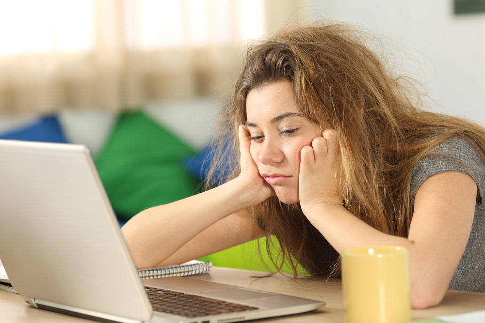 girl looking at her computer feeling hungover