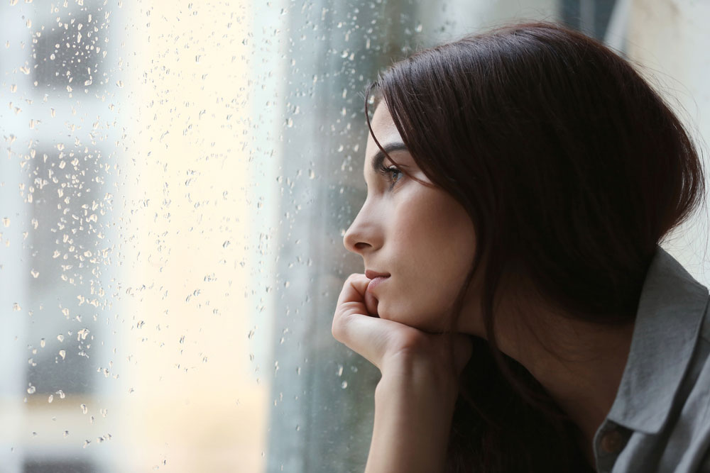woman looking out of the window on a rainy day
